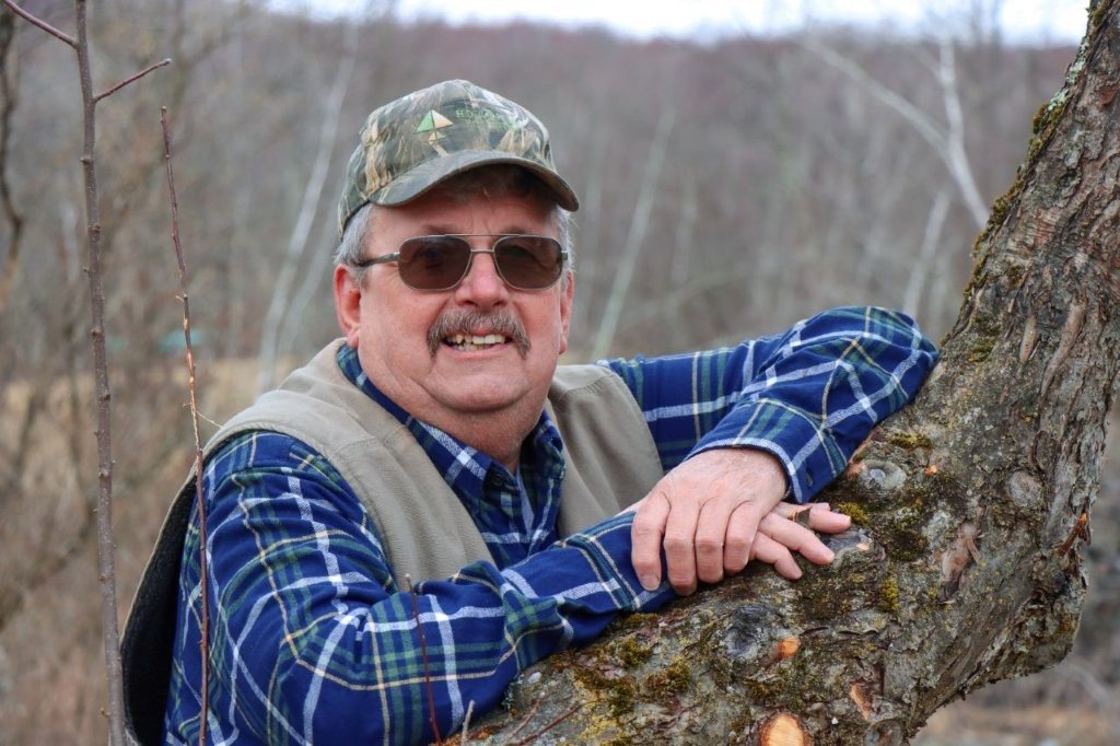 William Sargent leaning on a low tree branch in the woods